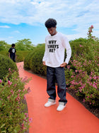 Model wearing white Why Always Me long-sleeve shirt with black lettering by MADEBYFUTBOL