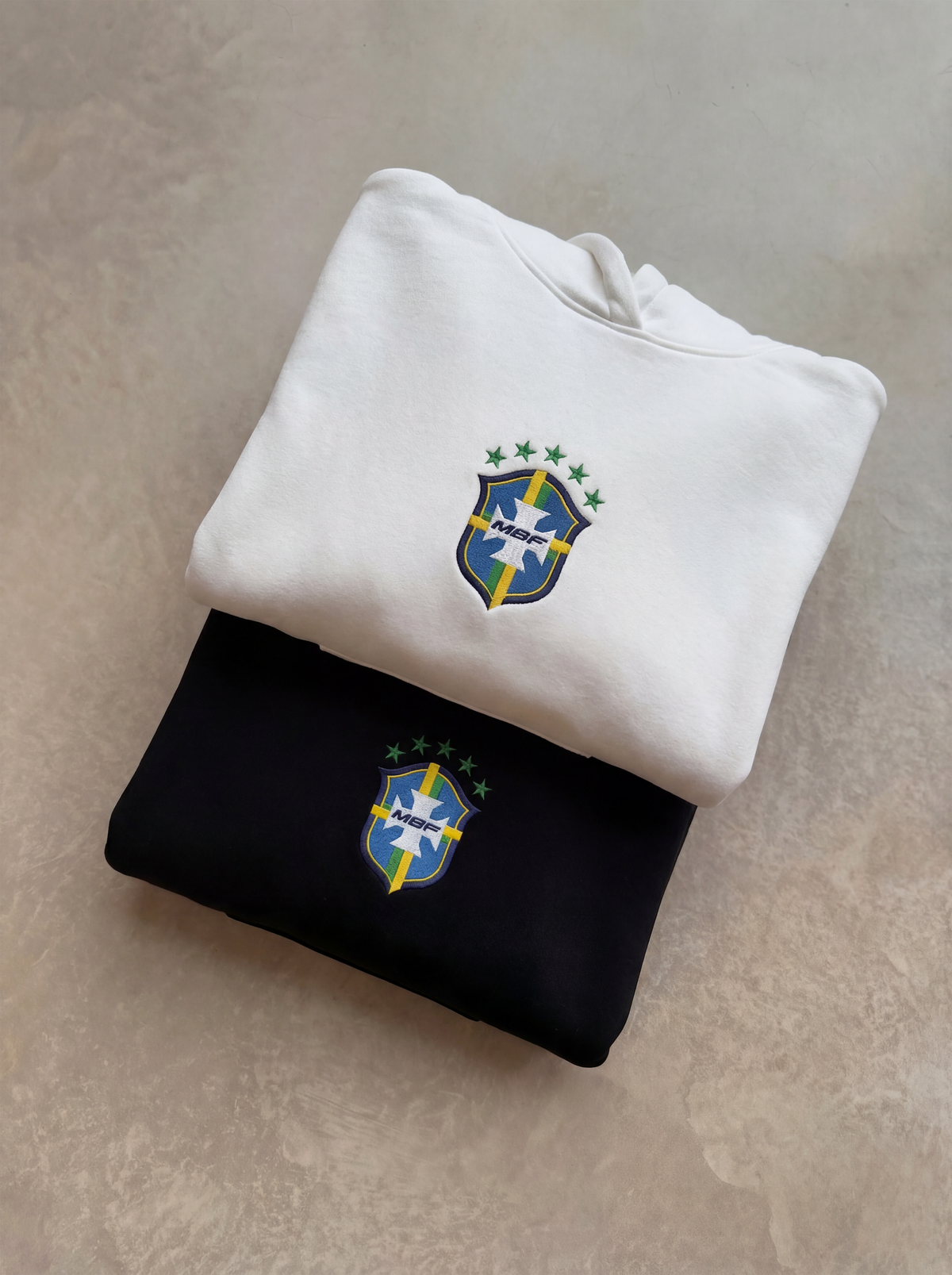 Folded white and black Brazil hoodies with chest crests by MADEBYFUTBOL